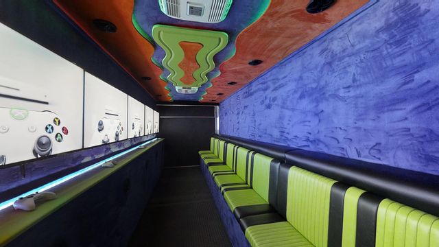 Interior of the Gamers Paradise gaming theater, lime bench seating facing a run of wall-mounted screens