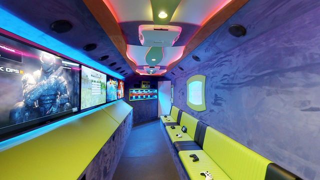 Interior of the Gamers Utopia gaming theater, lime bench seating and a run of screens down one side