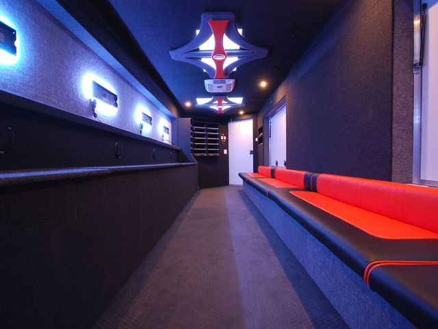 Finished interior of a gaming theater in red and black with LED lighting, screens mounted and bench seating installed