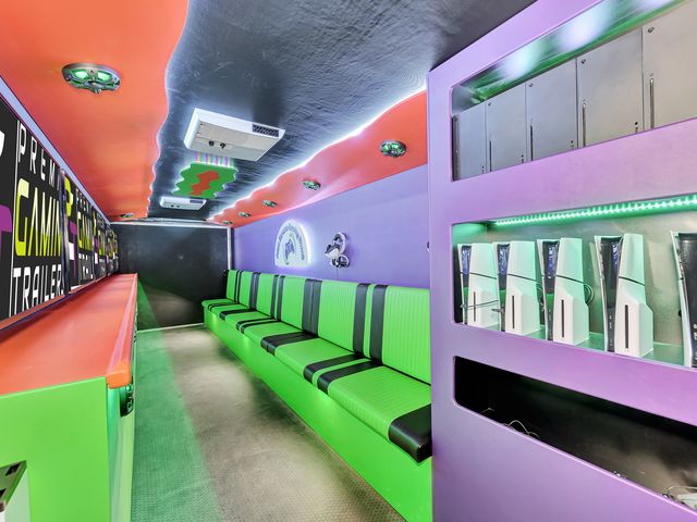 Completed gaming theater interior in green and purple with consoles racked, screens along one wall and bench seating