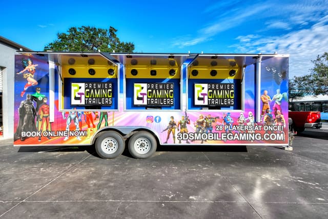 A Gamers Utopia from the side with three exterior screen hatches raised, a PGT screen under each and a row of speakers above it, and a full colorful custom wrap with illustrated characters along the body
