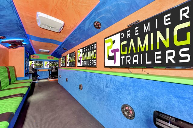 A long gaming trailer interior with lime and black diamond-quilted benches on the left, PGT screens above a blue suede wall on the right, an orange and blue ceiling, and two racing simulator seats at the far end