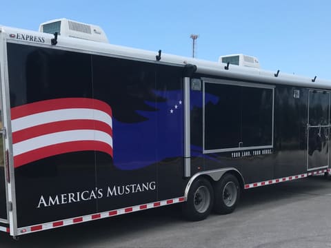 A finished full custom exterior wrap on a black gooseneck trailer: red and white flag stripes, a blue horse and the customer's own name down the side